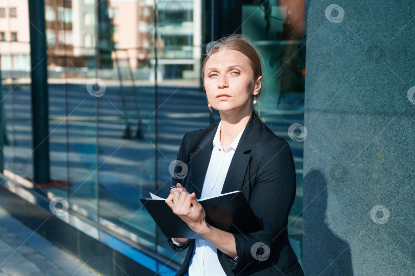Скачать Успешная красивая деловая женщина, стоящая на фоне зданий, пишет фотосток Ozero