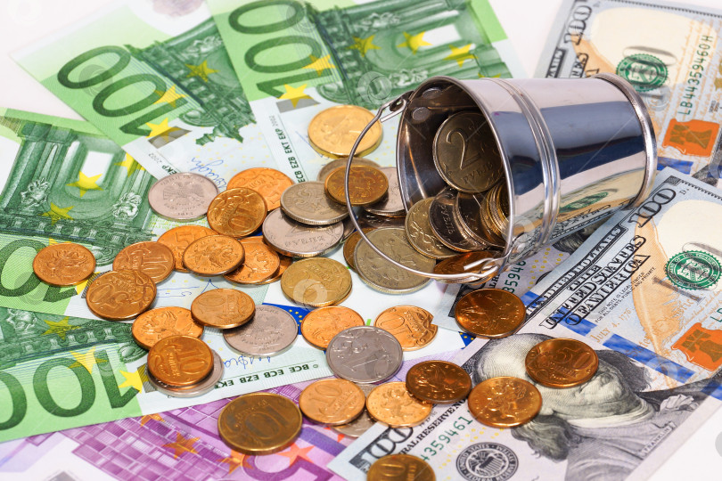 Скачать Банкноты евро , доллар и опрокинутое ведро с российскими монетами фотосток Ozero