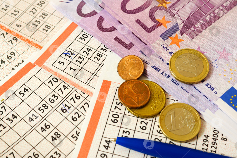 Скачать Выигрыш в лотерею. Банкноты и монеты евро лежат на лотерейных билетах фотосток Ozero