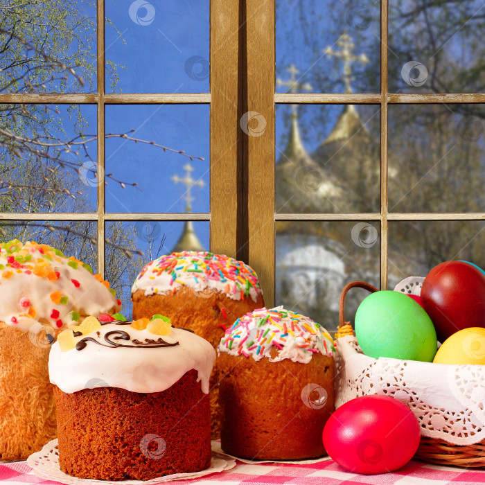 Скачать Пасха. Пасхальные куличи и разноцветные яйца на фоне витрины. За окном купол храма фотосток Ozero
