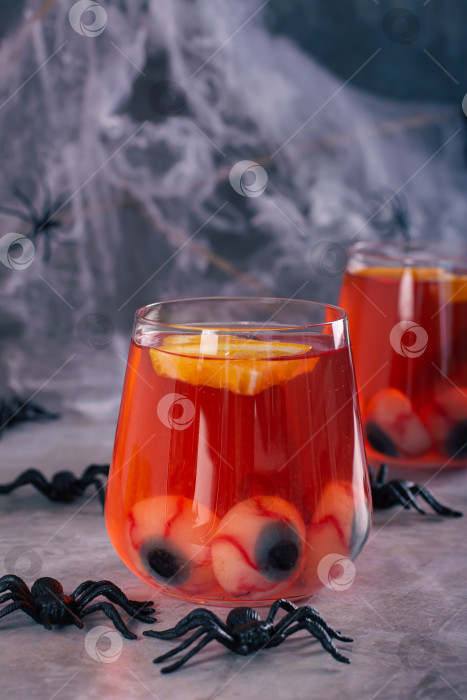 Скачать Безалкогольный красный коктейль с глазными яблоками и апельсином в бокалах o фотосток Ozero