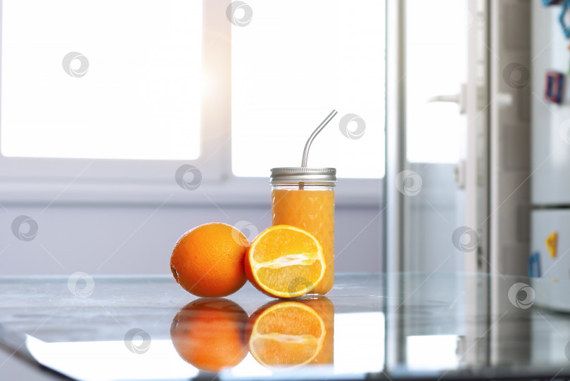 Скачать Фрукты апельсины и апельсиновый сок в интерьере кухни и стол из прозрачного стекла на белом фоне в лучах света фотосток Ozero