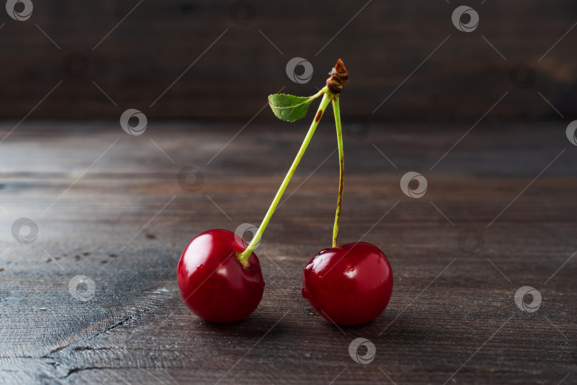 Скачать Спелые свежие ягоды вишни на ветке с листом на деревянном деревенском фоне. фотосток Ozero
