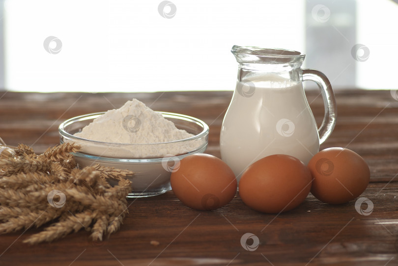 Скачать Молоко, пшеничная мука и яйца на темно-коричневом деревянном фоне в натуральных цветах фотосток Ozero