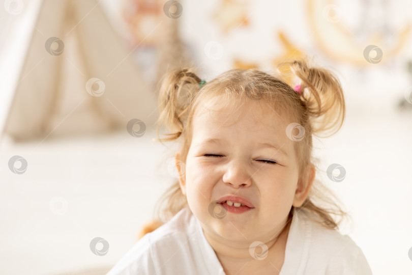 Скачать портрет крупным планом маленькой девочки-блондинки с голубыми глазами, улыбающейся в детской комнате фотосток Ozero