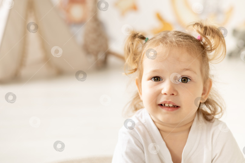 Скачать портрет крупным планом маленькой девочки-блондинки с голубыми глазами, улыбающейся в детской комнате фотосток Ozero