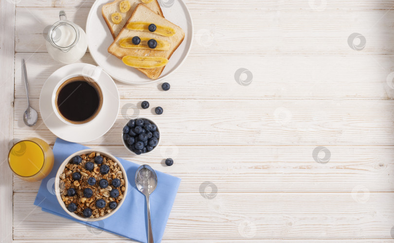 Скачать Завтрак с гранолой и черникой, кофе, молоком с апельсиновым соком, запеченными тостами на белом столе flatlay copy space фотосток Ozero