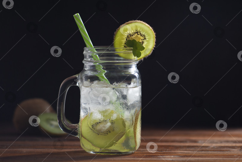 Скачать Лимонад со льдом и соком в стакане с украшением из нарезанного киви, листьев мяты и зеленой соломки фотосток Ozero