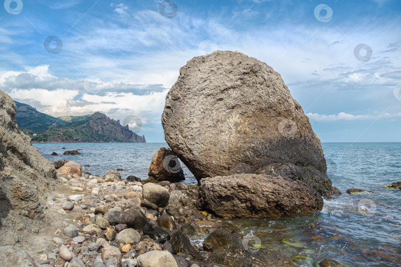 Скачать Огромный камень валун в воде на фоне моря, неба и гор. фотосток Ozero