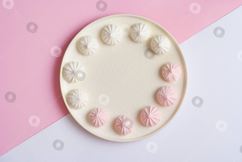Скачать Розово-белая тарелка со сладким десертным печеньем безе плоско уложенным вид сверху фотосток Ozero