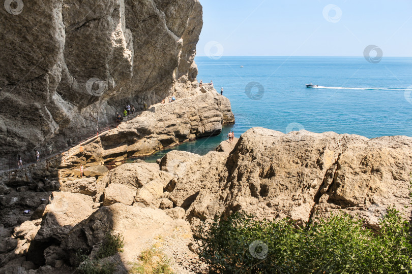 Скачать Люди под скалой на берегу моря. фотосток Ozero