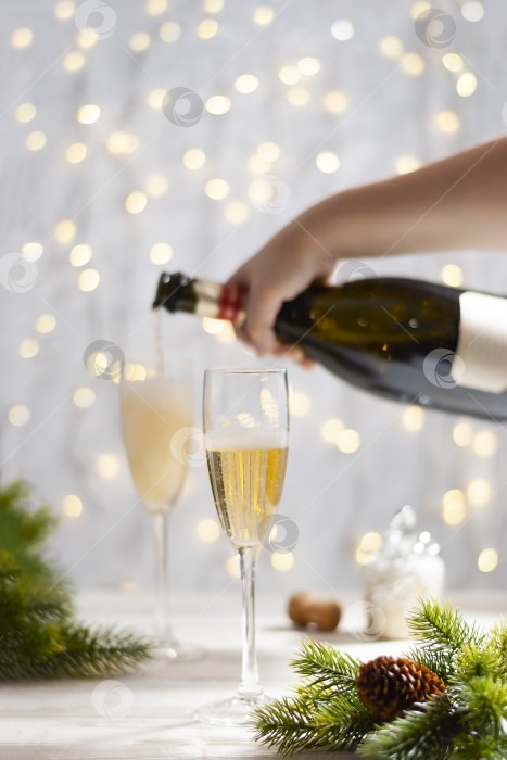 Скачать Ручное наполнение бокалов шампанским за новогодне-рождественским праздничным столом фотосток Ozero