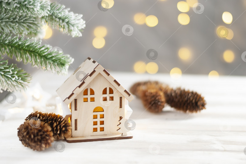 Скачать Игрушечный домик и рождественская елка с еловыми шишками, абстрактный светло-белый естественный праздничный фон с пространством для копирования фотосток Ozero