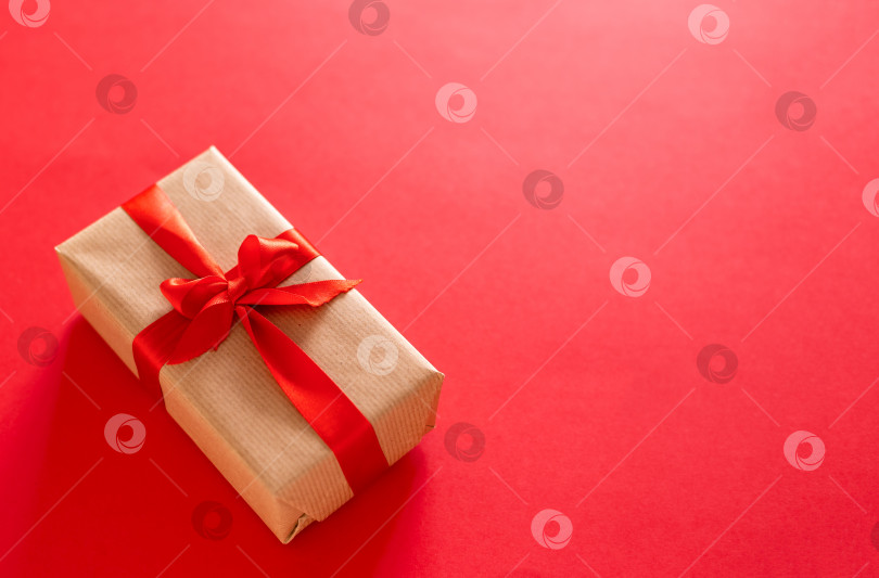 Скачать Высокий угол подарочной коробки, обернутой красной лентой, выделенной на красном фоне фотосток Ozero