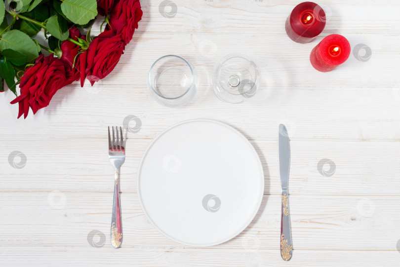 Скачать Романтическая сервировка стола в деревенском стиле на деревянном столе, украшенном букетом роз и красными свечами фотосток Ozero