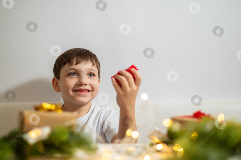 Скачать Милый маленький мальчик на Рождество дарит красную подарочную коробку. фотосток Ozero