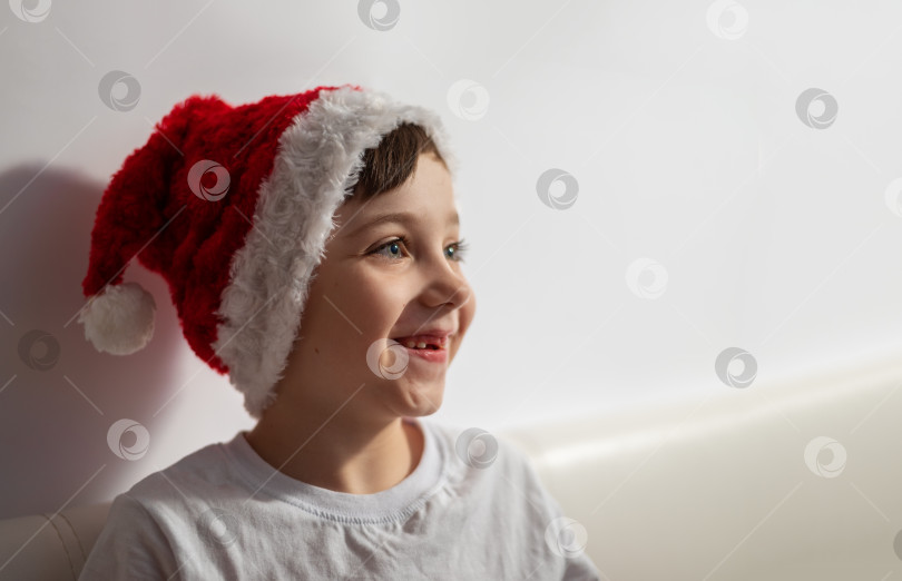 Скачать Веселый улыбающийся маленький ребенок мальчик в рождественской шляпе смотрит направо с пробелом для копирования фотосток Ozero