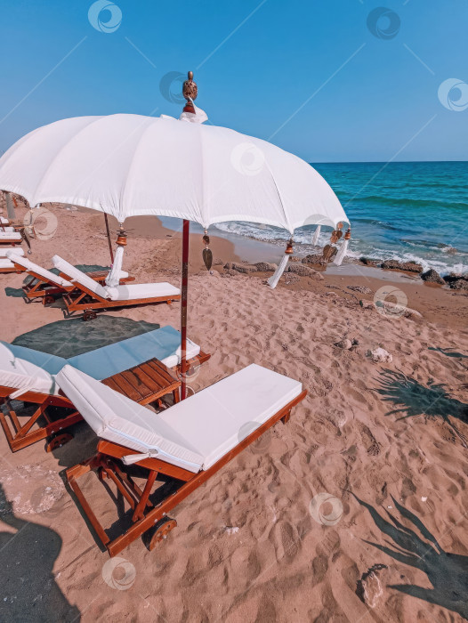 Скачать Деревянные шезлонги с матрасами и пляжными зонтиками на песчаном пляже фотосток Ozero