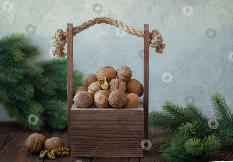 Скачать Деревянная коробка с грецкими орехами на деревянном столе с зимними ветками рождественской елки фотосток Ozero