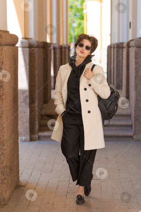 Скачать Портрет молодого европейского туриста в солнцезащитных очках, одетого в белое пальто и черный фотосток Ozero