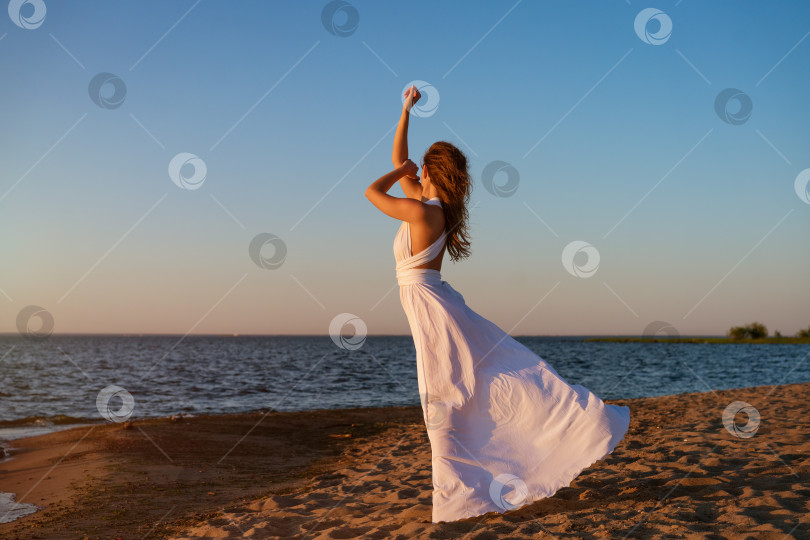 Скачать Молодая женщина летом в белом платье на берегу на закате фотосток Ozero