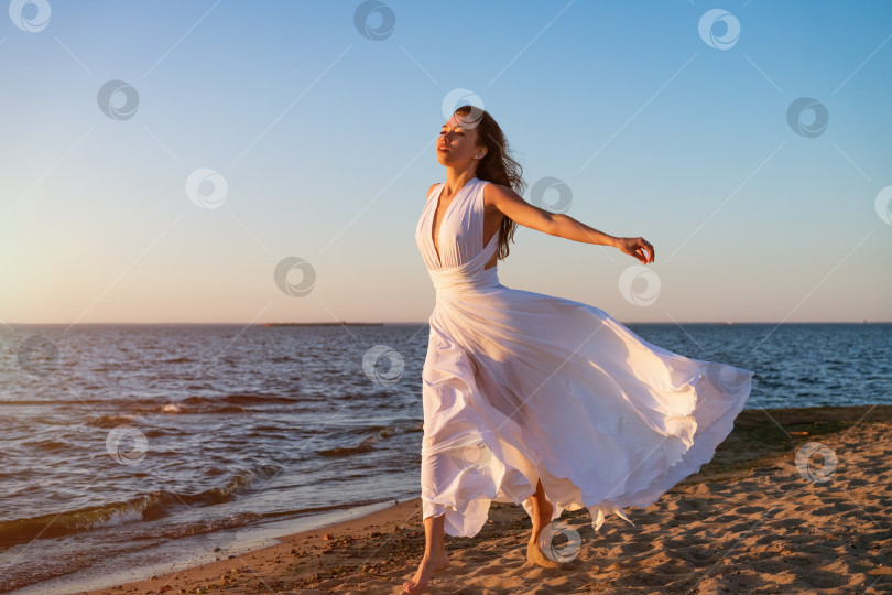 Скачать Молодая женщина летом в белом платье на берегу на закате фотосток Ozero