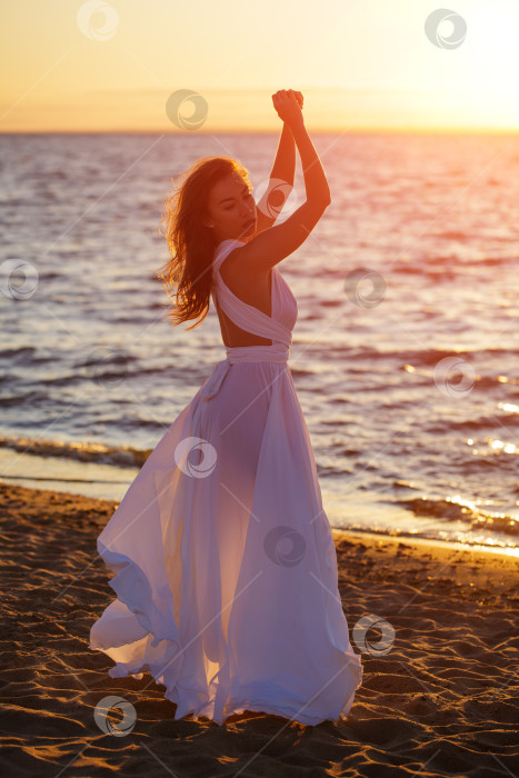 Скачать Красивая женщина позирует на пляже на закате в белом платье фотосток Ozero