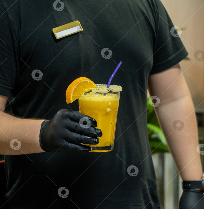 Скачать Вертикальный снимок крупным планом бармена, держащего стакан апельсинового dr. фотосток Ozero