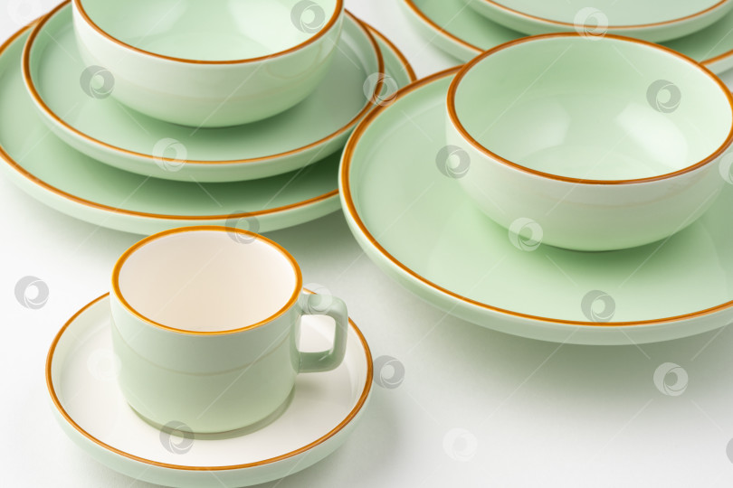 Скачать Набор белой и пастельно-зеленой керамической посуды с оранжевым оттенком фотосток Ozero