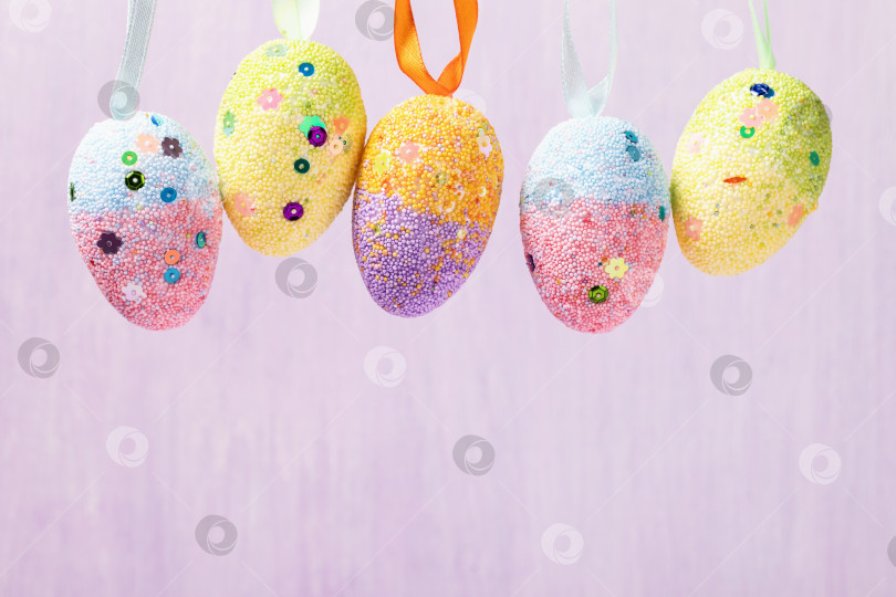 Скачать Висячие пасхальные яйца, украшенные различными цветами. Праздничный фон с пространством для копирования фотосток Ozero
