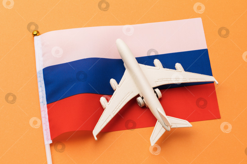 Скачать Флаг России и игрушечный самолет на оранжевом фоне, концепция на тему путешествия в страну фотосток Ozero