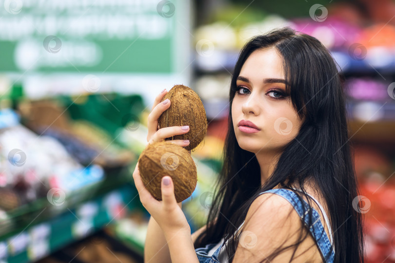 Скачать Девушка позирует с кокосовыми орехами в супермаркете фотосток Ozero