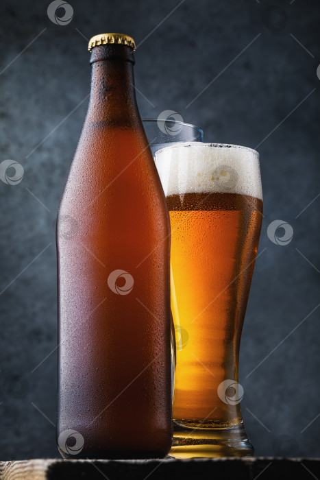 Скачать Бутылка светлого пива и полный стакан холодного напитка на деревянном столе, крупный план фотосток Ozero