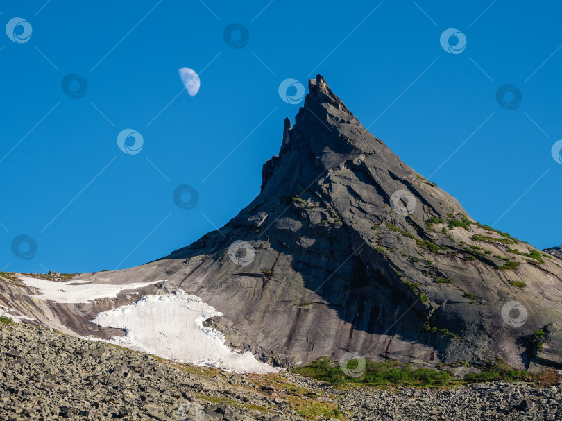 Скачать Остроконечный утес с небольшим снежным ледником, луна в голубом вечернем небе фотосток Ozero