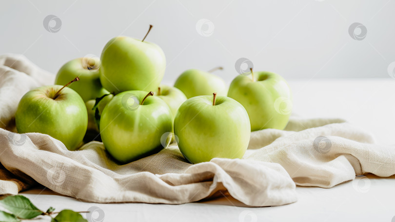 Скачать Зеленые яблоки на белом столе с льняной салфеткой на нейтральном фоне фотосток Ozero