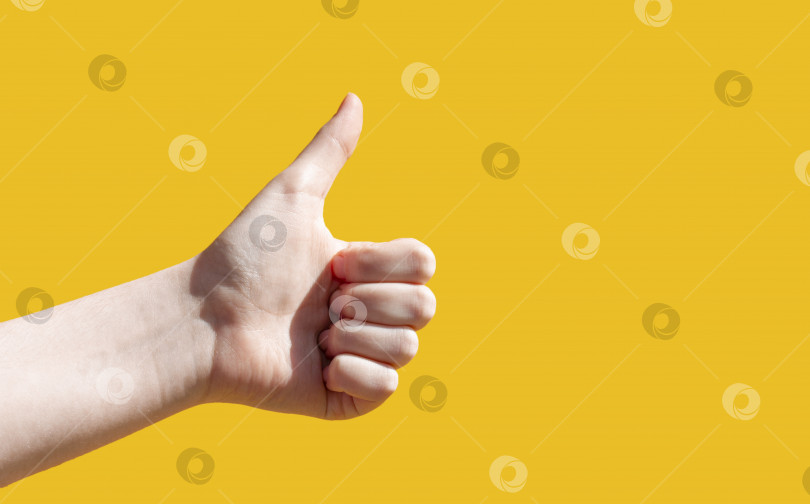 Скачать Крупным планом на желтом фоне рука показывает поднятый большой палец. Нравится это фотосток Ozero