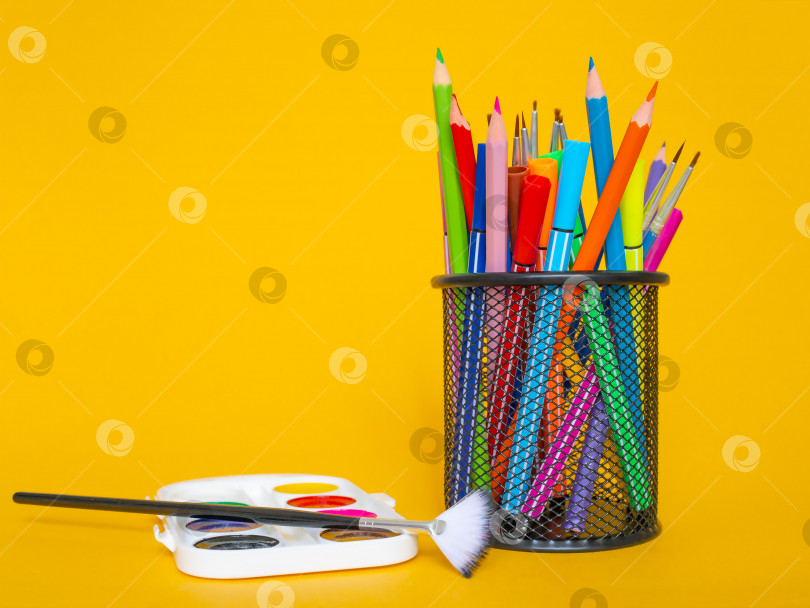 Скачать Цветные карандаши в пенале на желтом фоне с белым листом бумаги и красками фотосток Ozero
