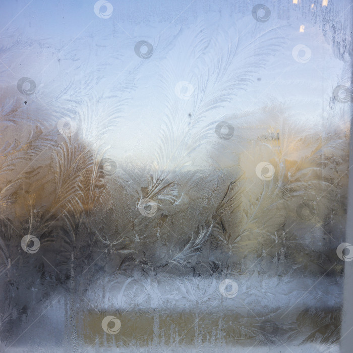 Скачать Вид на старый городской дом из замерзшего зимнего окна. Текстурные ледяные узоры на стекле. Избирательный фокус. фотосток Ozero