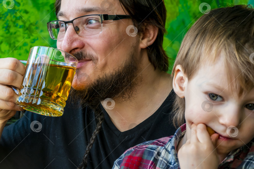 Скачать концепция утреннего семейного счастья. Отец и сын пьют чай на кухне, раскрашенной в виде леса. папа и сын веселятся. фотосток Ozero