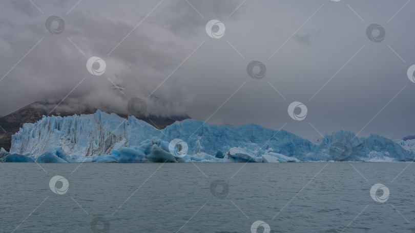 Скачать Стена голубого потрескавшегося льда возвышается над бирюзовым озером. фотосток Ozero