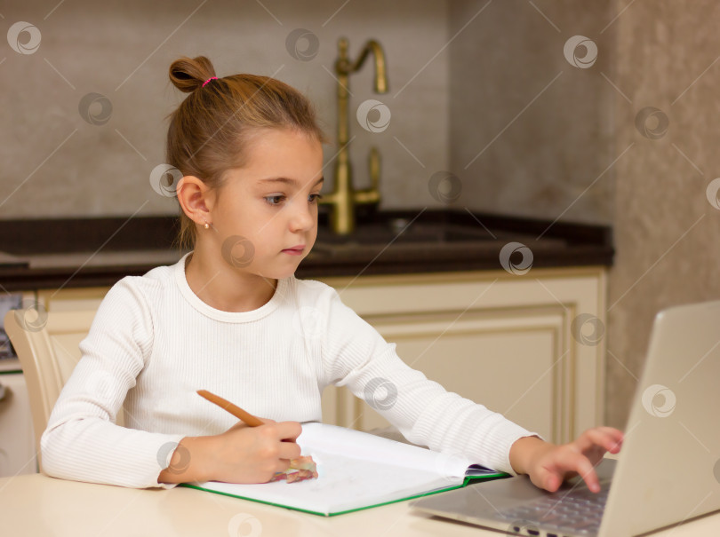 Скачать маленькая девочка 5 лет с ноутбуком и книгами, онлайн-обучение, смотрящее на экран компьютера, школьница, вебинар, слушающая лекцию, концепция домашнего обучения фотосток Ozero