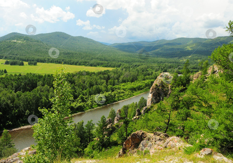 Скачать Вид с вершины горы на живописную летнюю долину, окруженную горами и текущей красивой рекой. фотосток Ozero