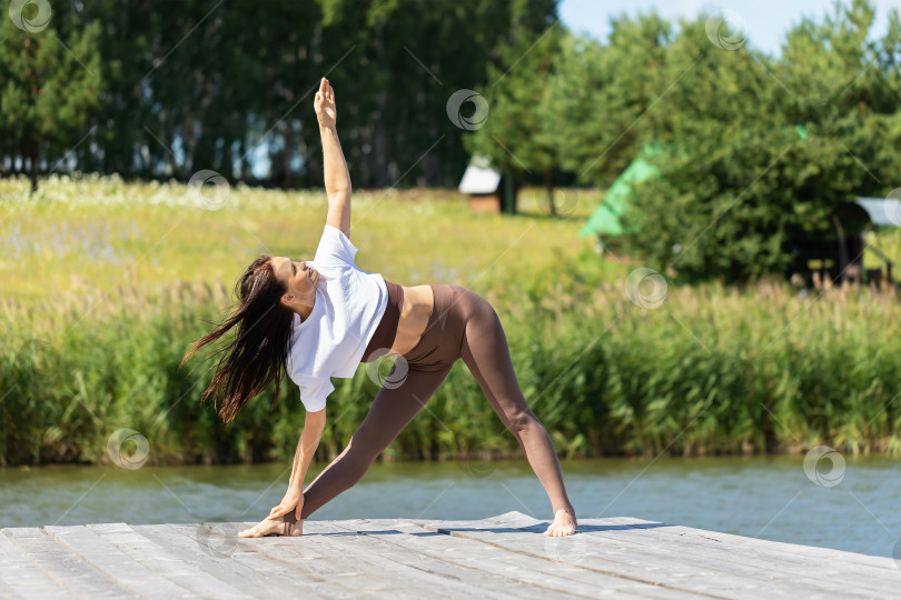 Скачать Женщина, ведущая здоровый образ жизни и практикующая йогу, выполняет фотосток Ozero
