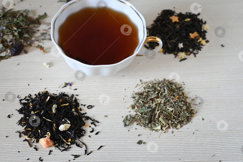 Скачать Набор разных сортов чая рядом с чайником, наполненным горячим заваренным чаем, на бежевом фоне. фотосток Ozero