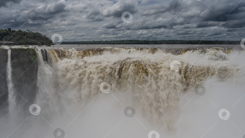 Скачать Мощные потоки водопада спускаются в ущелье, пенясь фотосток Ozero