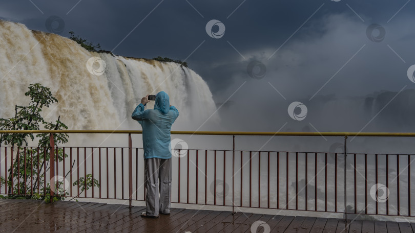 Скачать Мужчина стоит у перил смотровой площадки, фотографирует фотосток Ozero