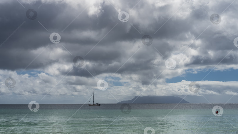 Скачать На фоне спокойного бирюзового океана виден силуэт лодки. фотосток Ozero