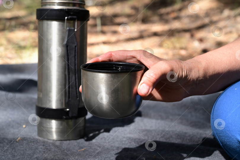 Скачать женские руки наливают чай из термоса в лесу на пикнике фотосток Ozero