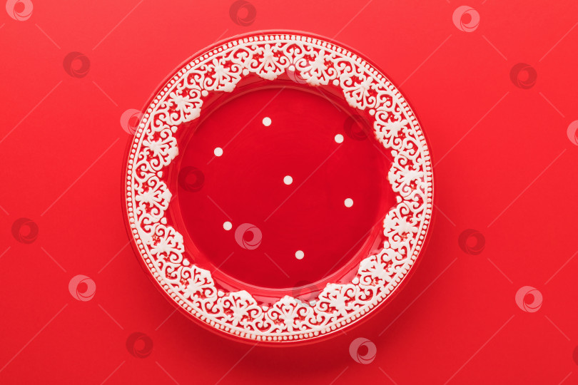 Скачать Пустая красная тарелка с новогодним рисунком на красном фоне, вид сверху фотосток Ozero