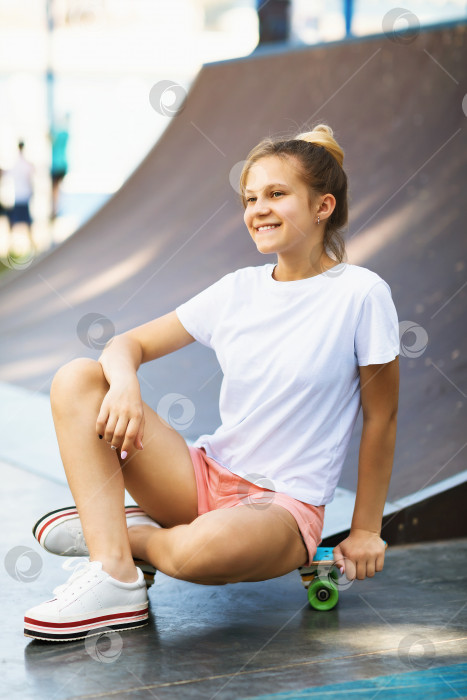 Скачать Удовлетворенная девушка-подросток отдыхает на скейтборде во время катания в парке фотосток Ozero